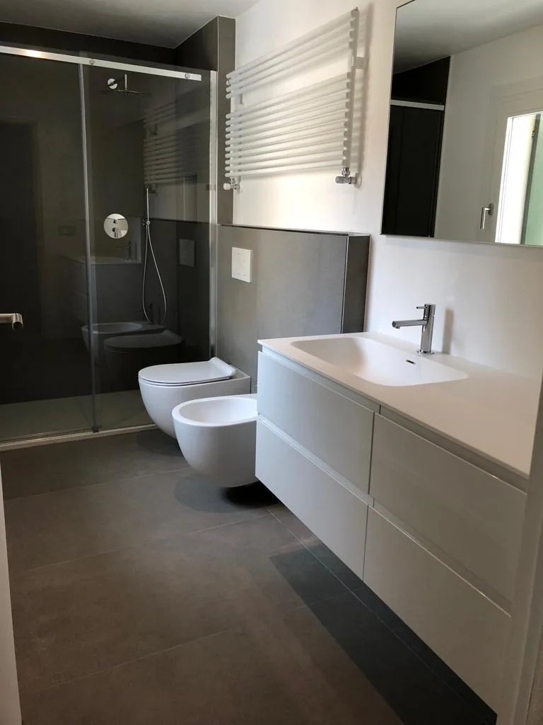Bagno ristrutturato Brugnolo Termoidraulica Padova con doccia in vetro, sanitari sospesi e radiatore scaldasalviette